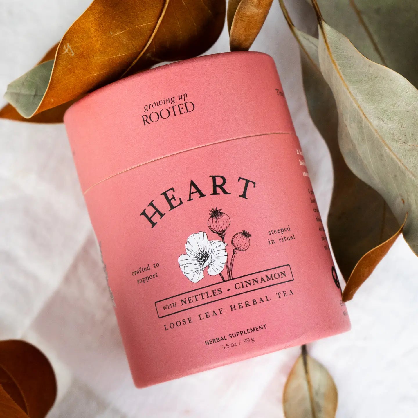 Pink tea canister labeled 'Heart' with botanical design on a white background with leaves.