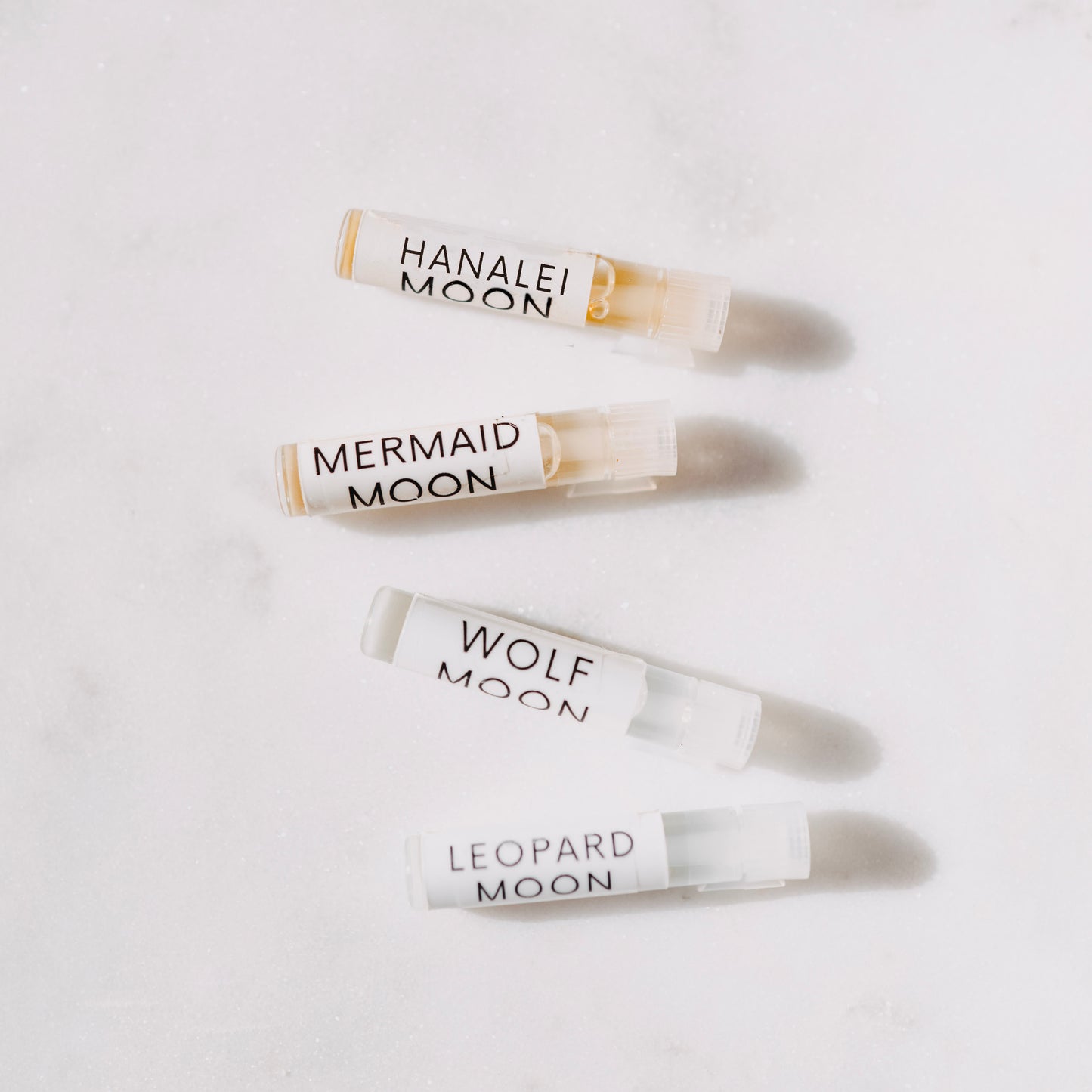 Four small glass bottles labeled 'Hana Lei Moon', 'Mermaid Moon', 'Wolf Moon', and 'Leopard Moon' on a light background.